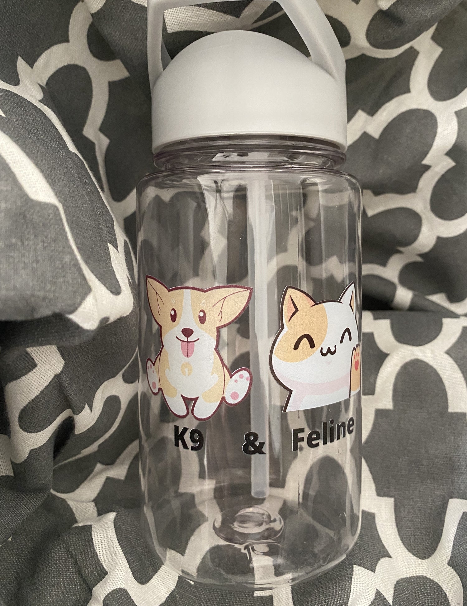 The 19.5 oz bottle with a cute cat and dog design. It is sitting on a soft fabric with white and grey patterns